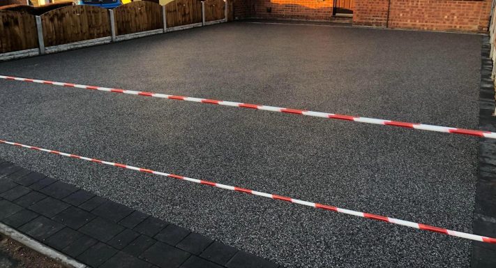 A flat, gravelled area with a red and white barrier tape marking boundaries.