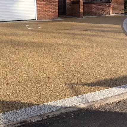 A RESIN driveway leading to a house, with a smooth white border.