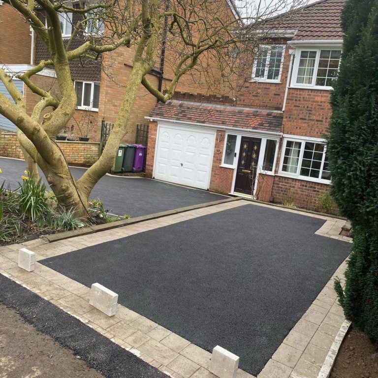 A residential property with a newly paved driveway and surrounding trees.